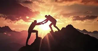 Two people climbing a mountain at sunset